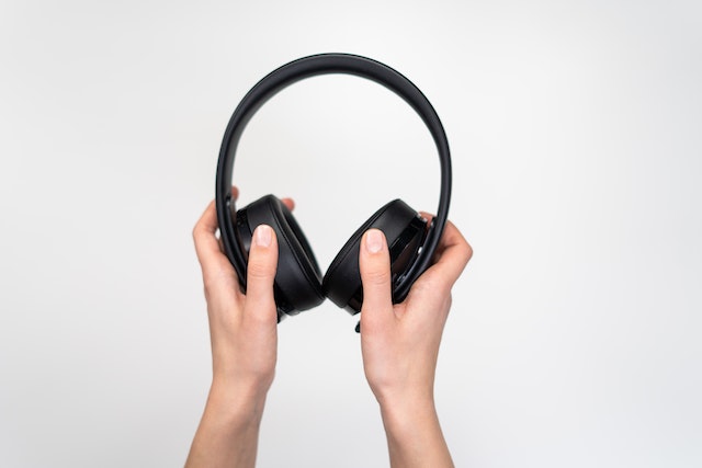 person holding a pair of black headphones
